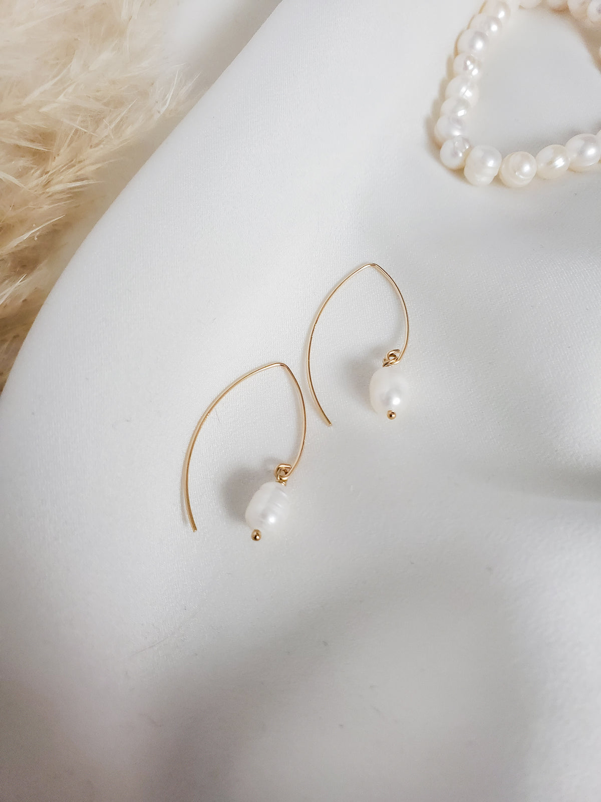 Pearl earrings with gold hooks on a white surface