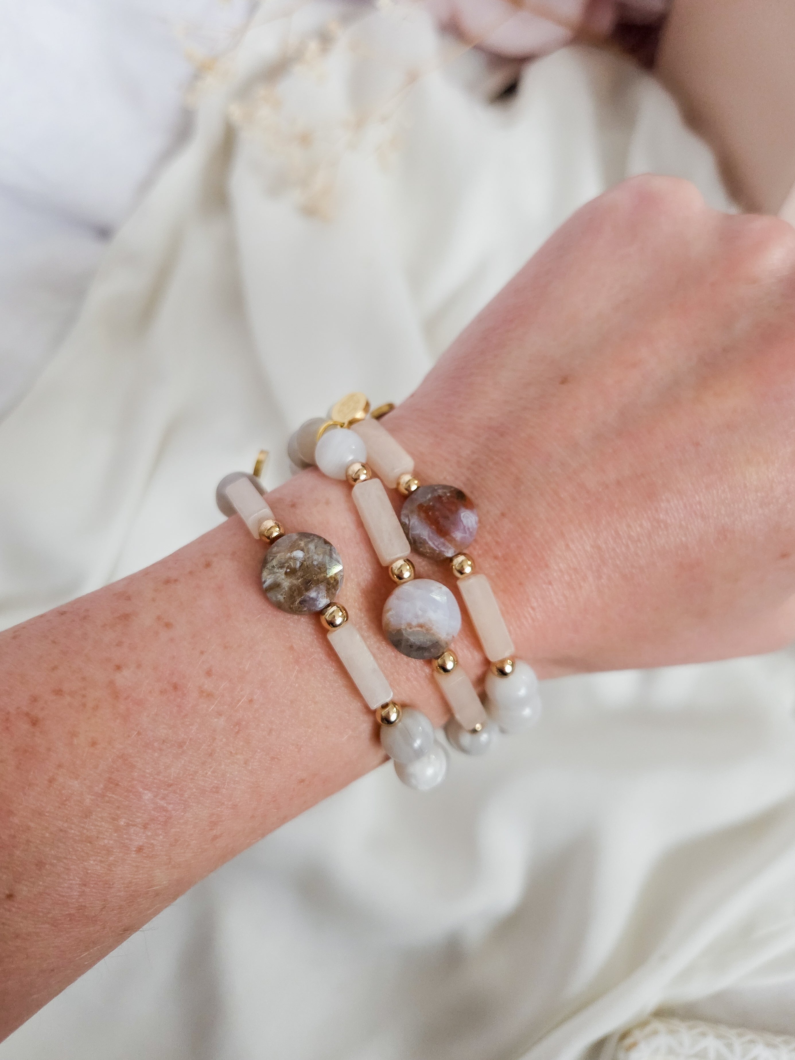 Close-up of a wrist wearing a beaded bracelet on a white fabric background