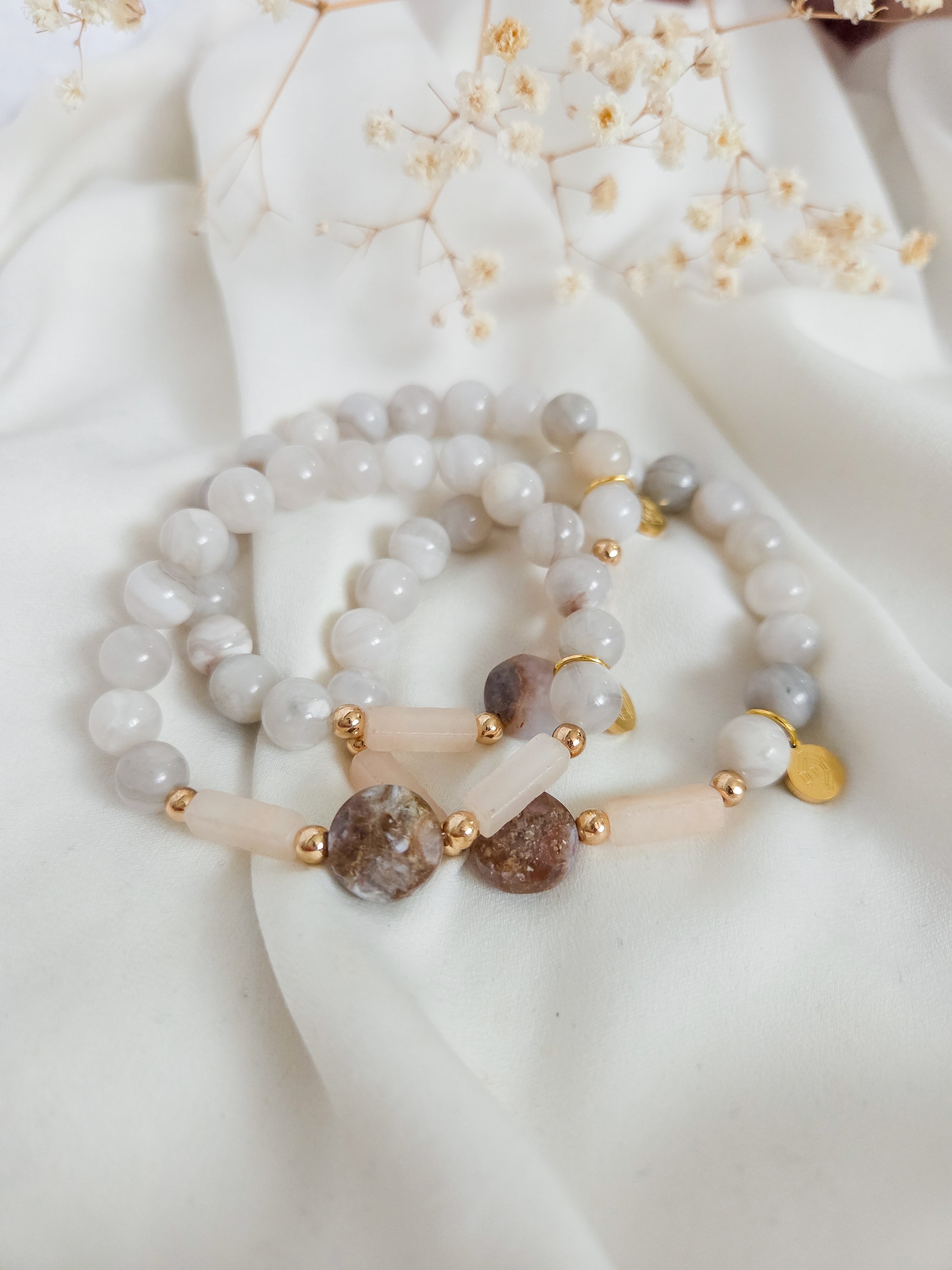 Set of beaded bracelets with gold accents on a white fabric background