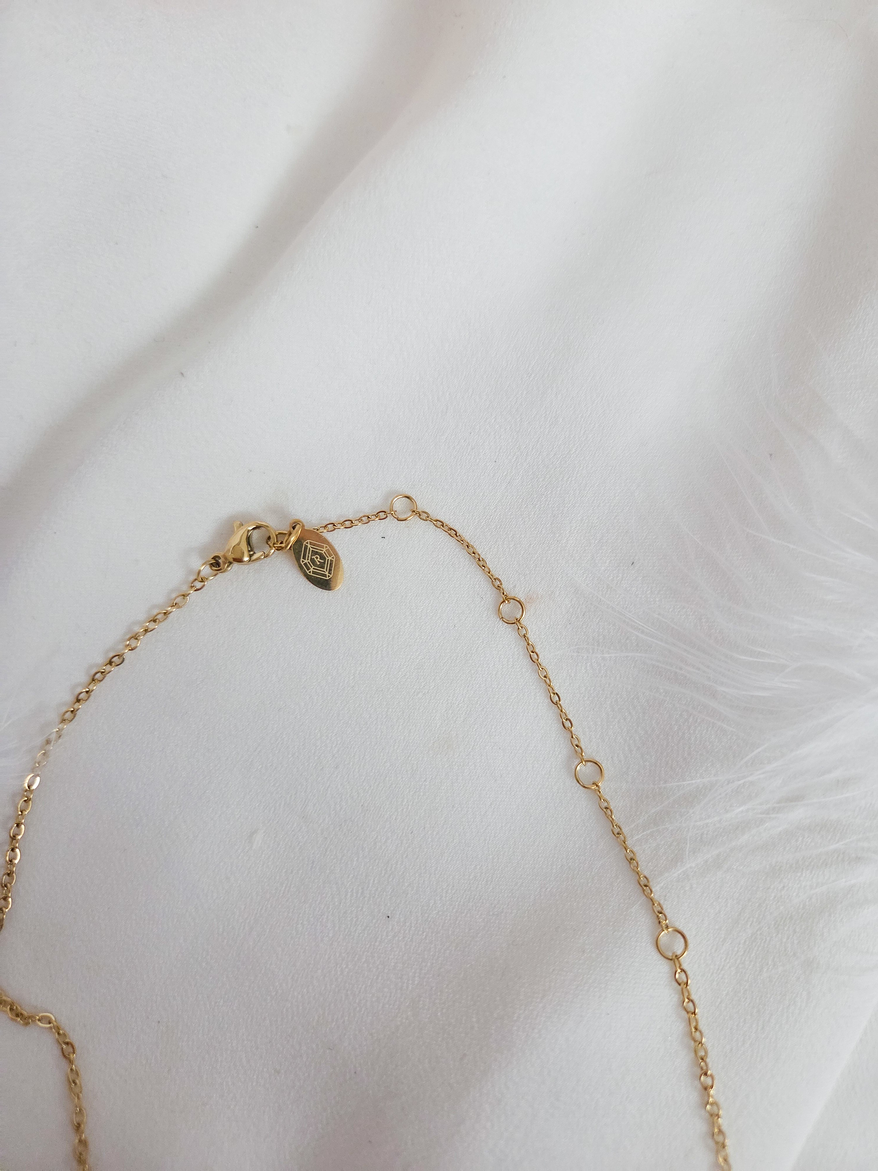 Lobster clasp and extender chain detail on pendant necklace with Rock Paper Pretty logo tag.