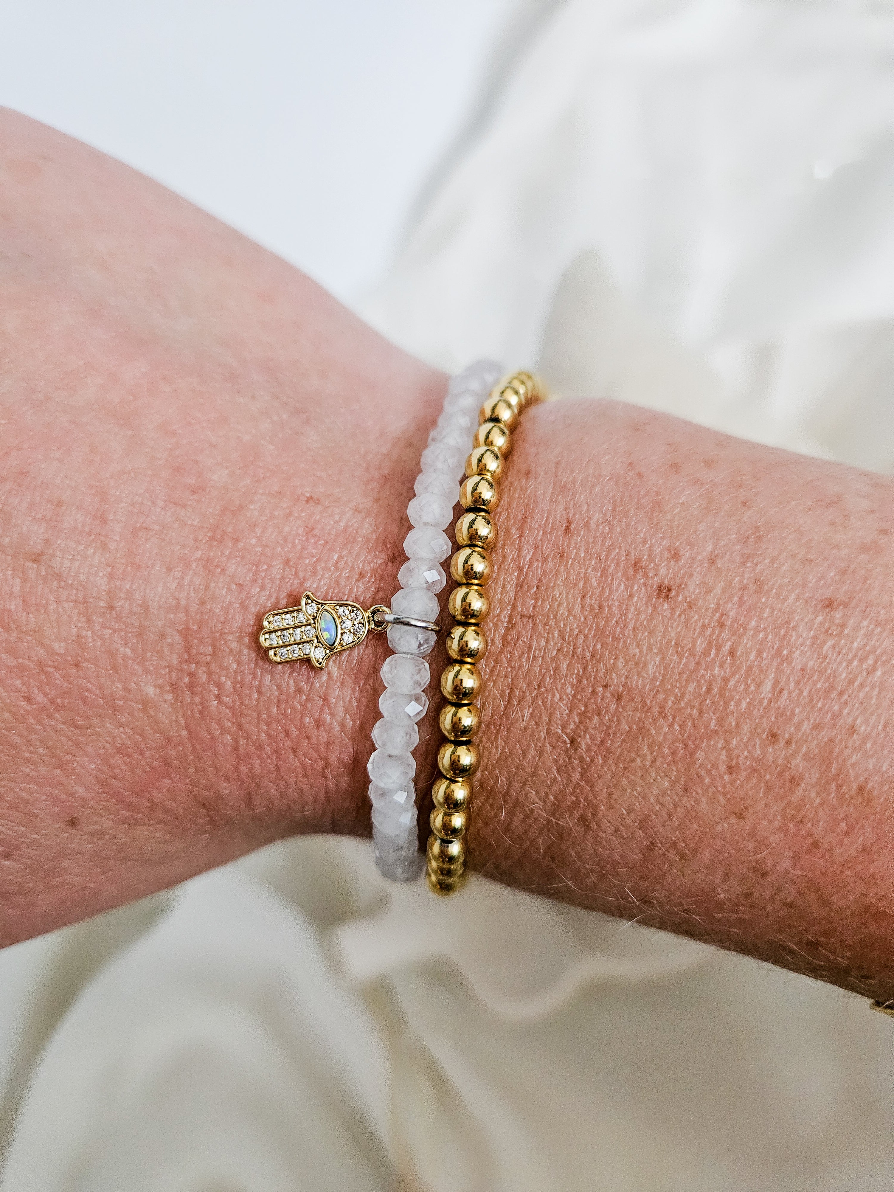 Gold beaded stretch bracelet worn on wrist.