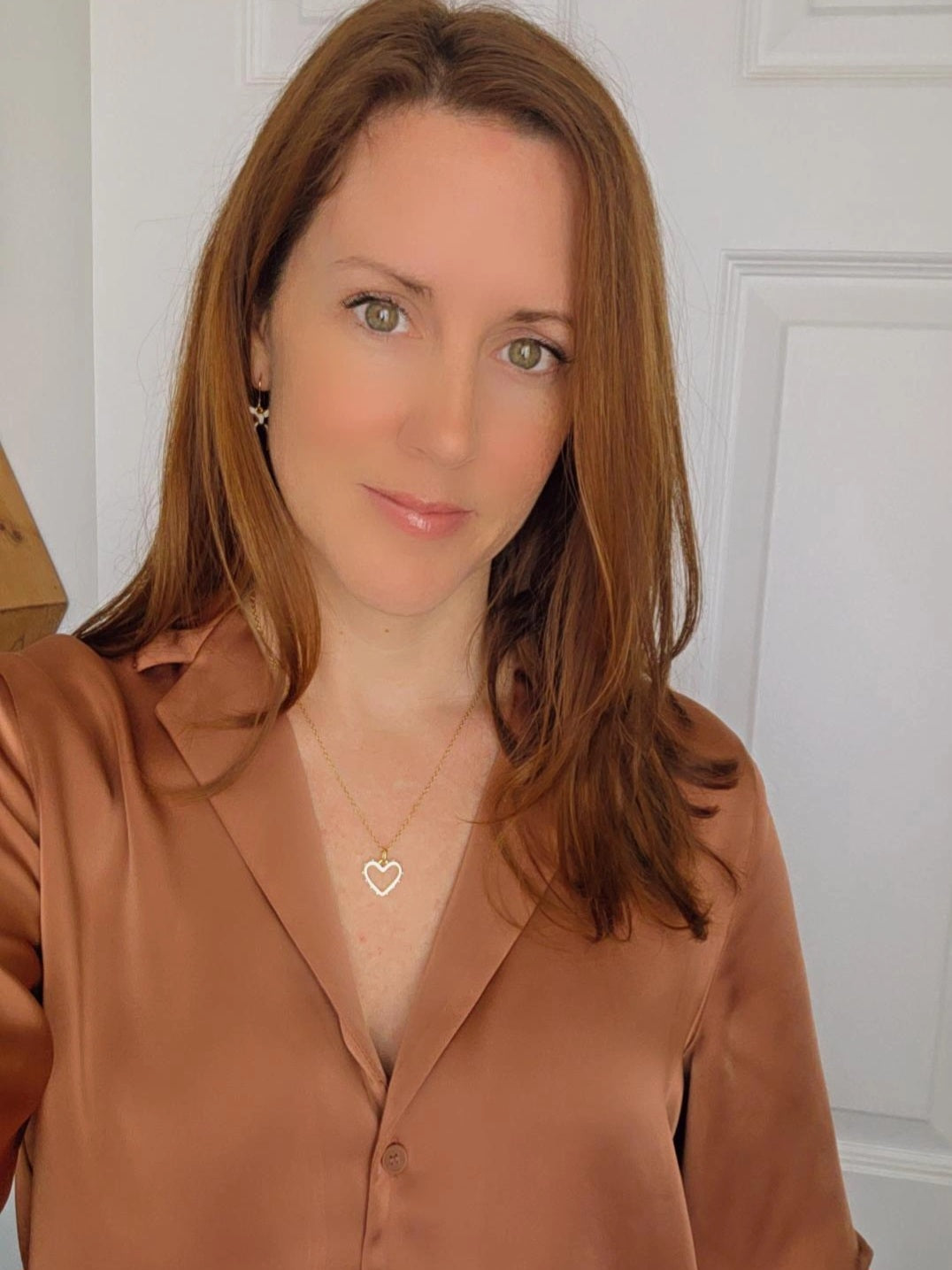 Woman wearing a brown blouse and a heart-shaped necklace, styled for everyday wear.