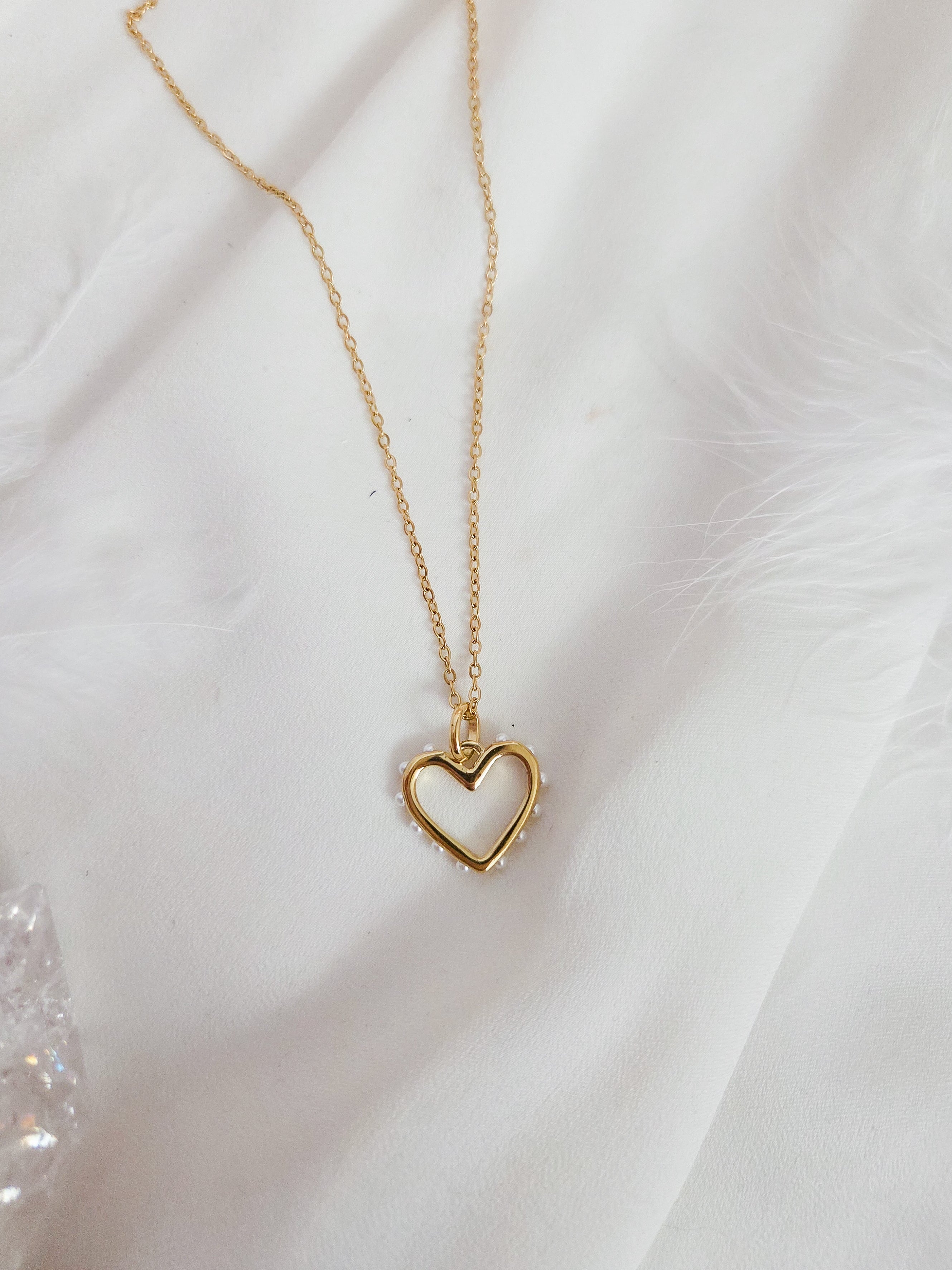Gold heart-shaped necklace on a white fabric background