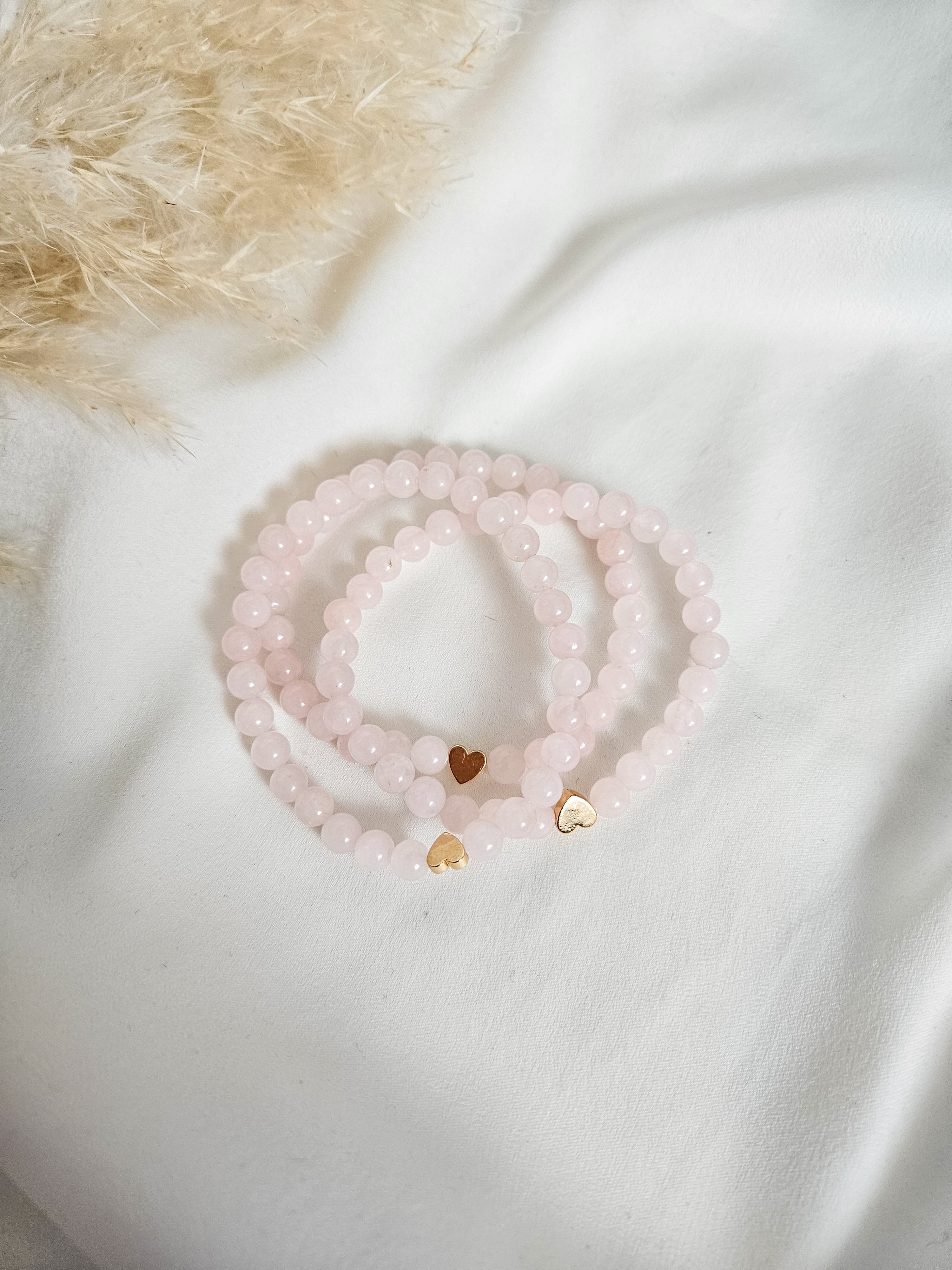 Light pink, rose quartz, gemstone beaded bracelets with gold plated hematite heart accent for gifting.