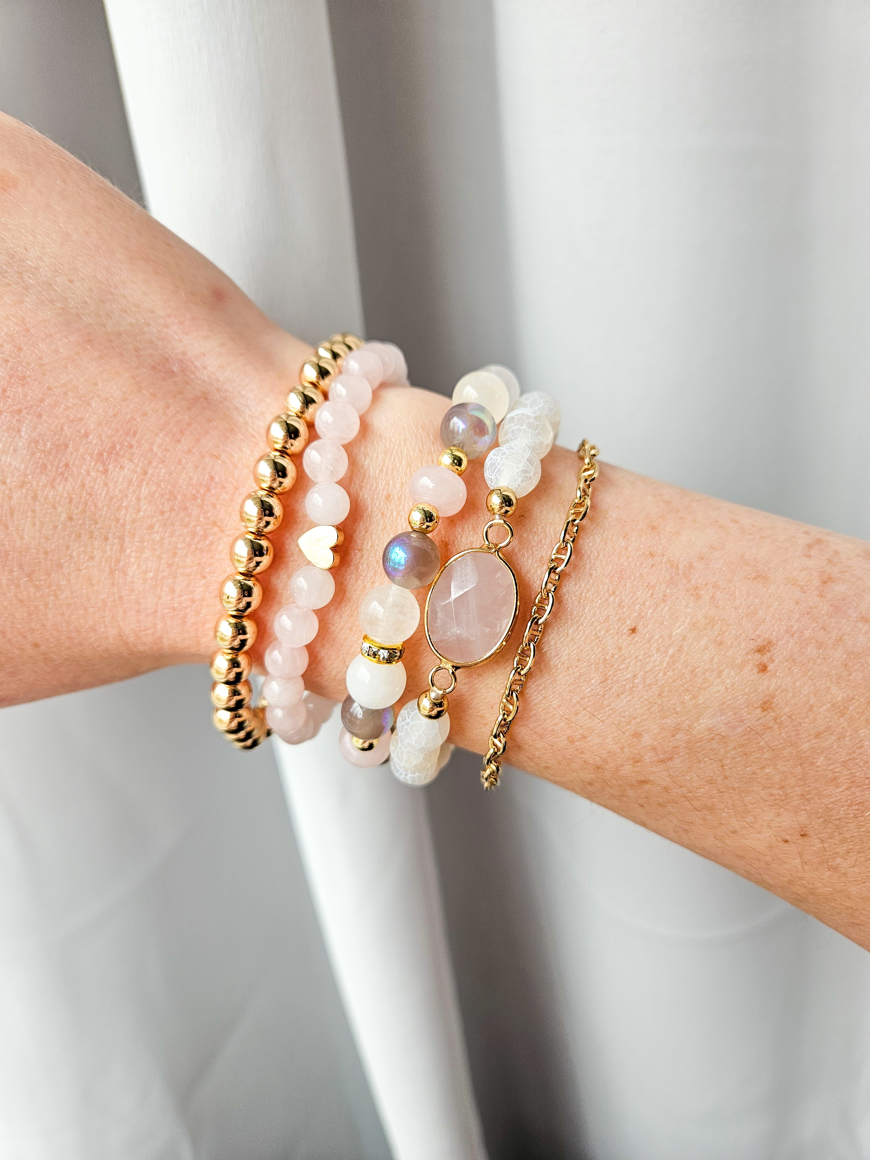 Rose quartz beaded stretch bracelet styled on wrist with everyday bracelets.