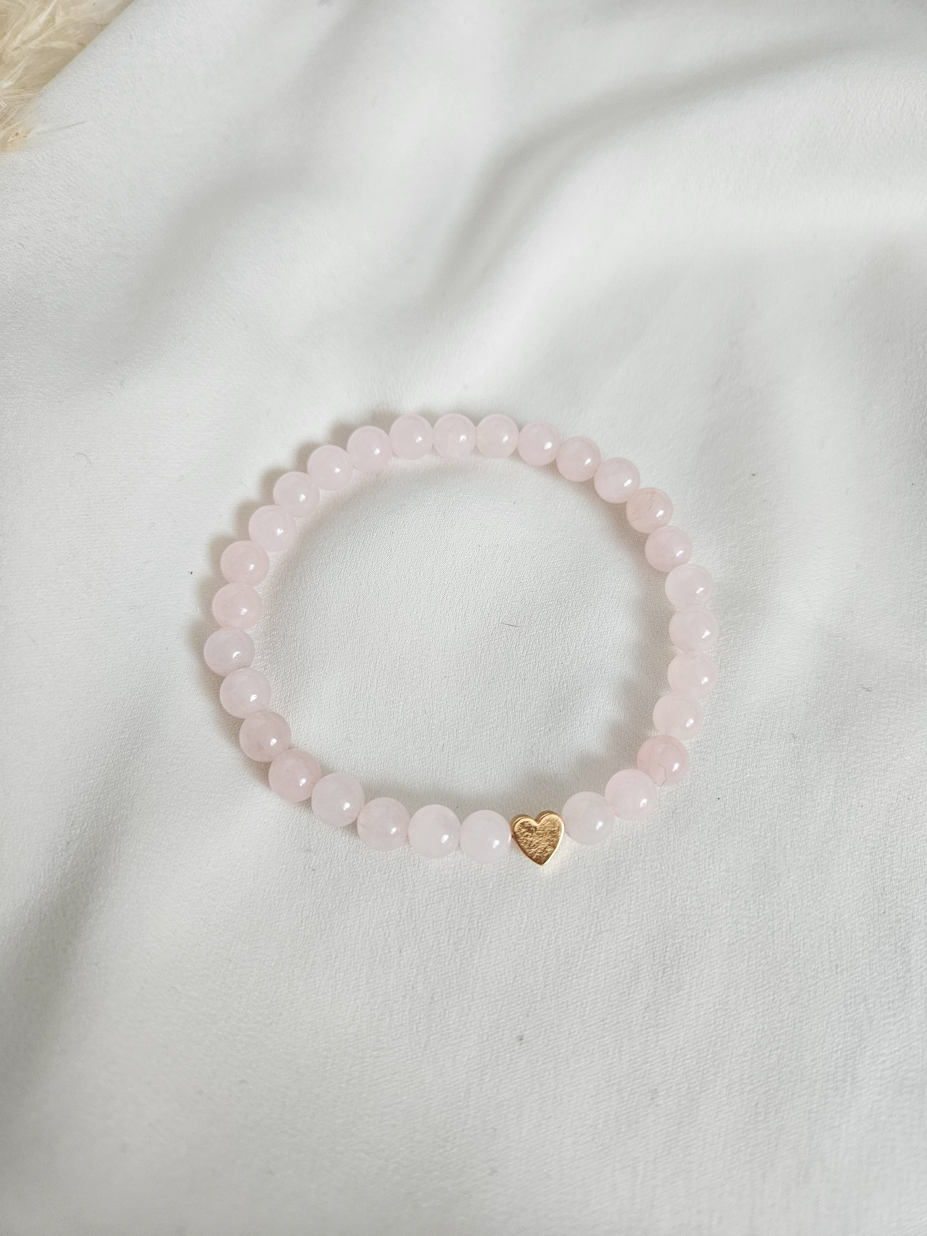 Rose quartz beaded stretch bracelet with gold heart detail.